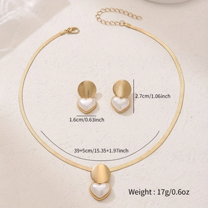 Golden heart jewelry set with snake chain necklace and earrings on stone background