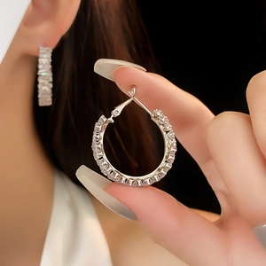Macro view of silver hoop earrings with rectangular zircon stones and secure clasp