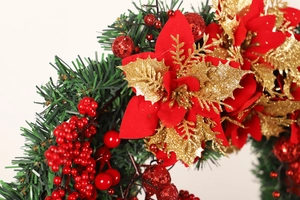 Close-up of Christmas wreath with red berries, velvet flowers, and golden accents