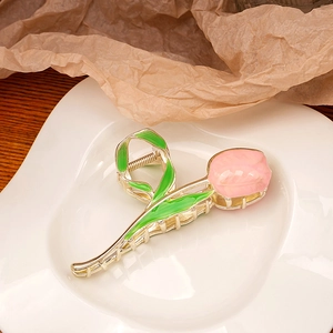 Close-up of golden tulip hair claw clip with pink petals and green enamel leaf detail