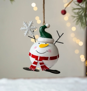Festive metal snowman ornament with red scarf and green hat hanging by twine on tree