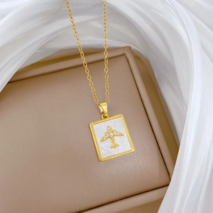 Detailed macro of a gold titanium necklace with a shell plane pendant on white silk