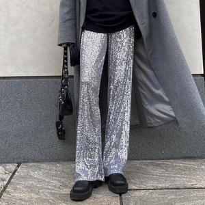 Close-up of silver sequin wide-leg trousers paired with black platform shoes for party wear