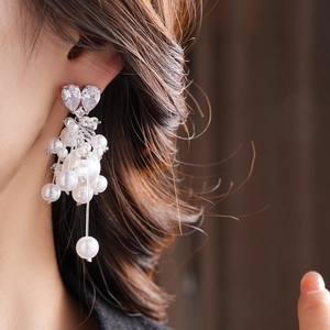 Close-up of heart-shaped zircon earrings with cascading pearls and long tassel design