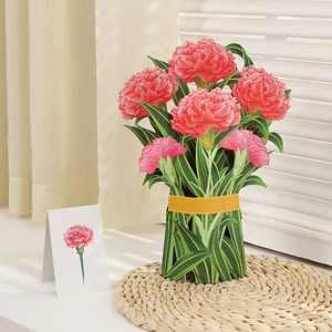 Detail shot of 3D pop-up pink carnation flower bouquet card with yellow ribbon on woven mat