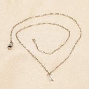 Silver stainless steel necklace with letter A pendant on champagne satin background