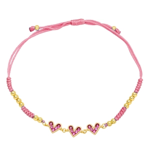 Detail of pink hand-woven cord bracelet with three gold heart pendants and zircons