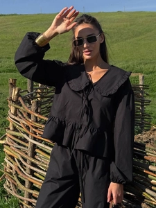 Détail du col volanté et du laçage sur un ensemble deux pièces noir en coton pour femme