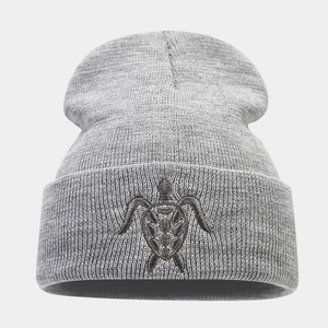 Close-up of a grey beanie featuring detailed turtle embroidery and a thick knit texture