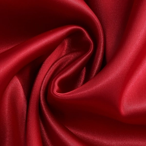 Vue détaillée du tissu en satin rouge foncé avec un drapé en spirale élégant et soyeux