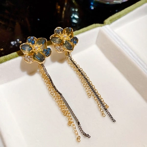 Detail of floral crystal earrings with blue gemstones and long metallic tassel chains