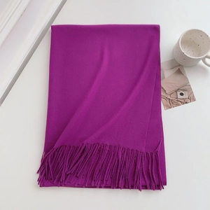 Detailed view of a soft purple cashmere scarf with fringe on a white tabletop set