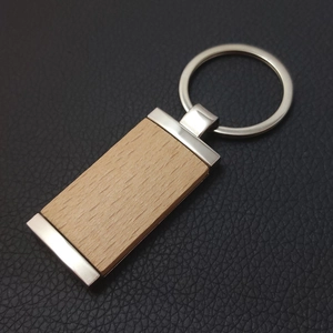 Detailed view of rectangular beech wood keychain with metal edges on black leather