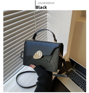 Close-up of black PU leather shoulder bag with a gold metal buckle and hand-held strap