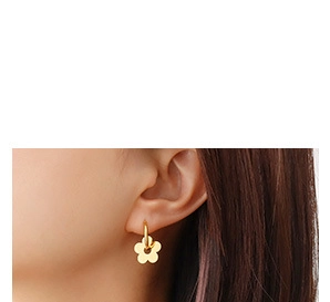 Close-up of a gold-plated flower charm earring on model showing minimalist jewelry style
