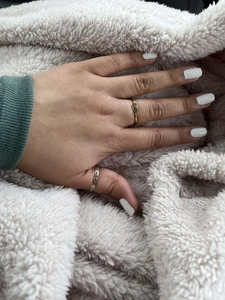 Close-up of gold snake ring and gemstone ring styled on fingers over plush fabric