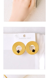 Detail of golden stainless steel hoop earrings with black square stone inlay