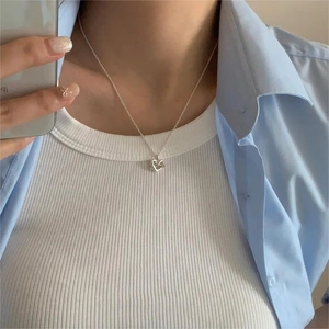 Close-up of minimalist sterling silver heart pendant necklace on a woman neck