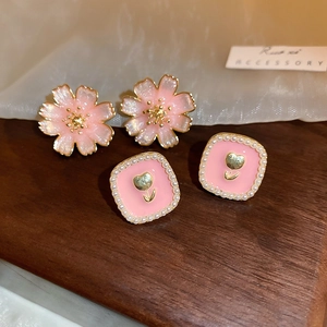 Detail of pink floral earrings and tulip charms with pearls on a wooden display