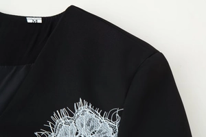 Détail d'une robe noire à col en V avec dentelle blanche et étiquette de taille M