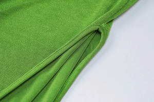 Gros plan détaillé de la fente latérale sur la robe verte en maille et texture du tissu