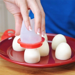 Close-up of a hand using a silicone egg boiler to remove a boiled egg on a red plate