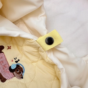 Close-up of quilted fabric with cute cartoon dog embroidery and yellow snap button strap