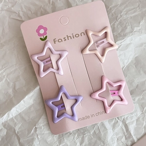 Set of four star-shaped matte hair clips in pastel pink and purple colors on a card