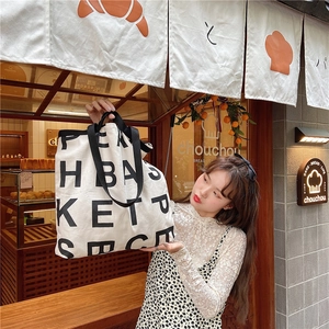 Lifestyle shot of large capacity canvas tote bag with bold artistic letter prints