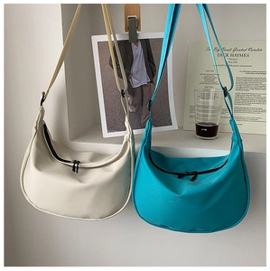 Detailed view of cream and bright blue nylon crescent bags with adjustable straps