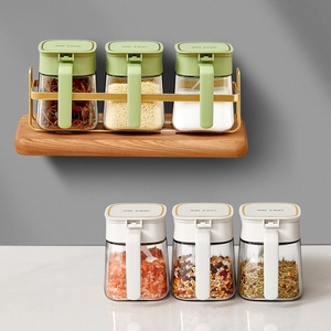 Kitchen spice jar set with clear glass bottles in green and white lids on a gold metal rack
