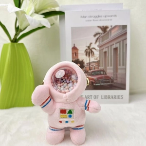 Roze pluche astronauten hanger met gekleurde kralen in de helm op een decoratieve achtergrond