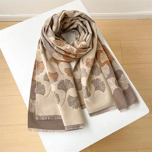 Detail of soft beige and brown gradient scarf with ginkgo leaf pattern and tassels