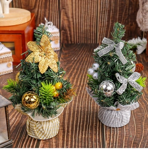 Close-up of mini gold and silver artificial Christmas trees on a dark wooden table