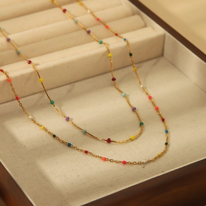 Collana a catena dorata con perle colorate vivaci presentata su un vassoio per gioielli