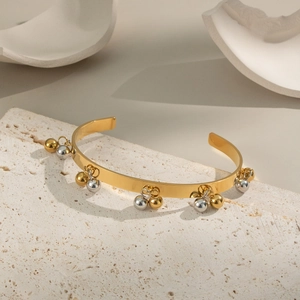 Dettaglio di ciondoli a sfera bicolore oro e argento su bracciale placcato oro 18K