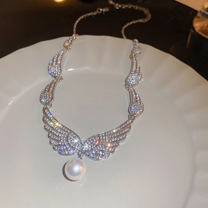 Detailed view of silver angel wing necklace with sparkling rhinestones and white pearl drop