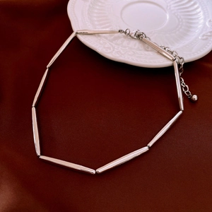 Detail view of a vintage silver-plated tubular metal necklace on dark velvet background