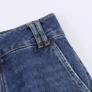 Détail de la taille du jean bleu foncé avec coutures orange et texture délavée