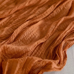 Orange cheesecloth table runner with rustic pleated texture for boho wedding decor