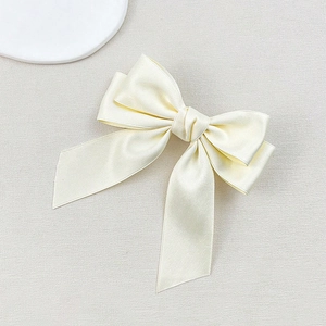 Detail of a creamy satin double-layered bow hair clip with a smooth glossy texture