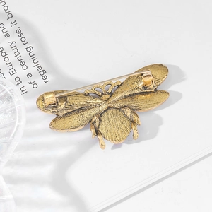 Vintage gold bee brooch with rhinestones and pearls shown from a back view with safety pin
