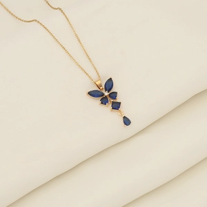 Macro detail of a gold butterfly necklace with deep blue gemstones on beige fabric