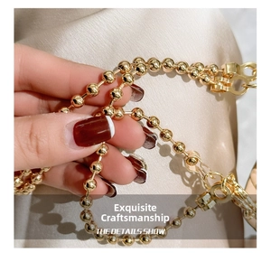 Detail of elegant gold bead chain strap with lobster clasp on luxury silk background