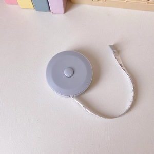 Overhead view of a compact grey portable measuring tape with a flexible 1.5m scale