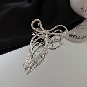 Macro shot of silver bow knot metal hair claw clip with minimalist geometric lines