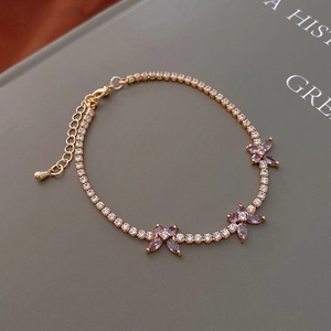 Detail view of gold chain bracelet with purple marquise zircon butterflies and lobster clasp