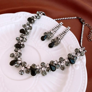 Macro view of teardrop crystal necklace and earrings set on white ceramic tray