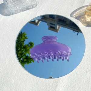 Detail of purple translucent jelly claw clip reflecting sky on a mirror surface