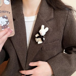 Detail of a white flocking rabbit brooch with a brown velvet bow on wool blazer lapel